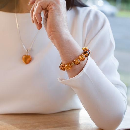 Shiny amber bracelet with gold-plated logo pendant